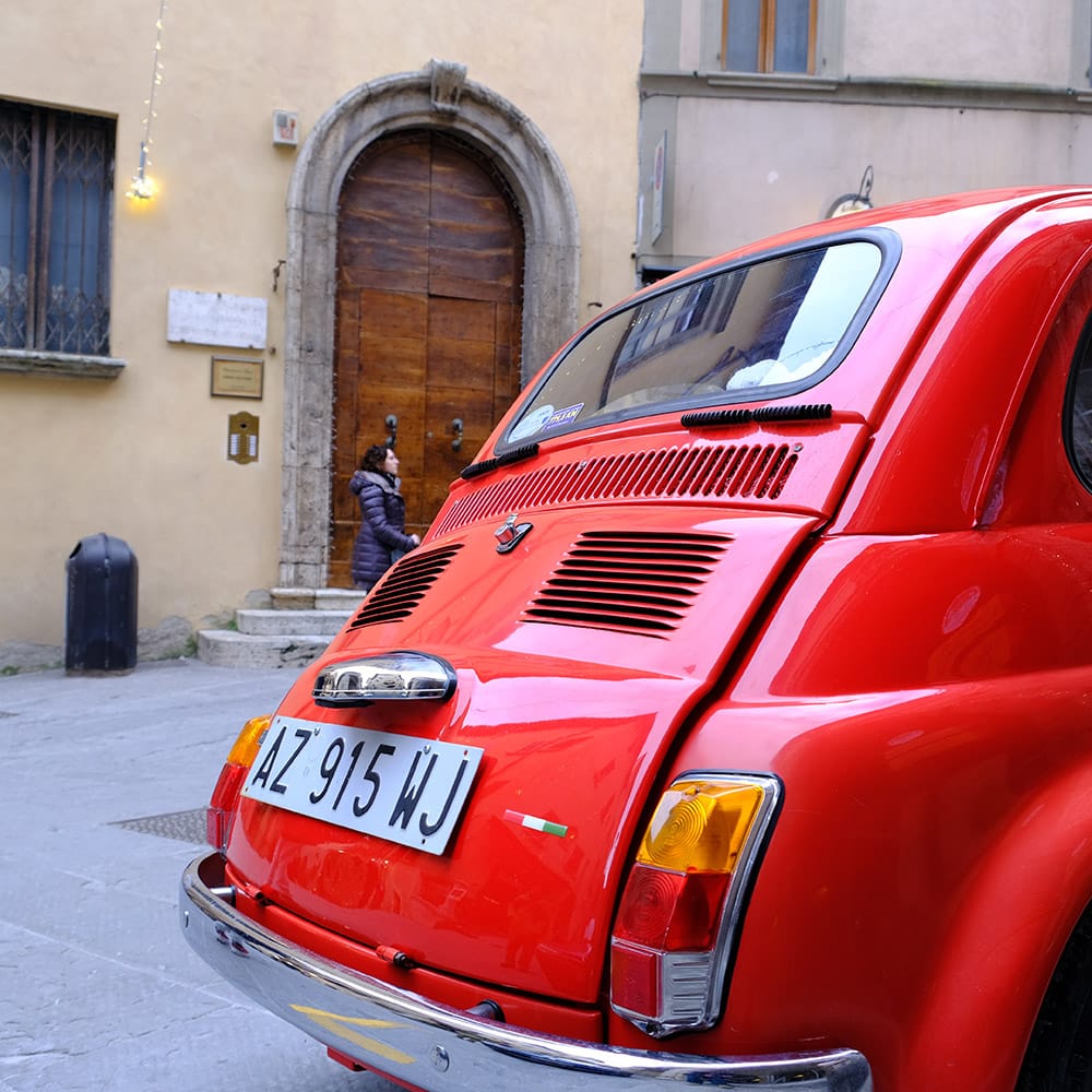 Coche Cinquecento rojo antiguo en la calle de un pueblo de Toscana Italia